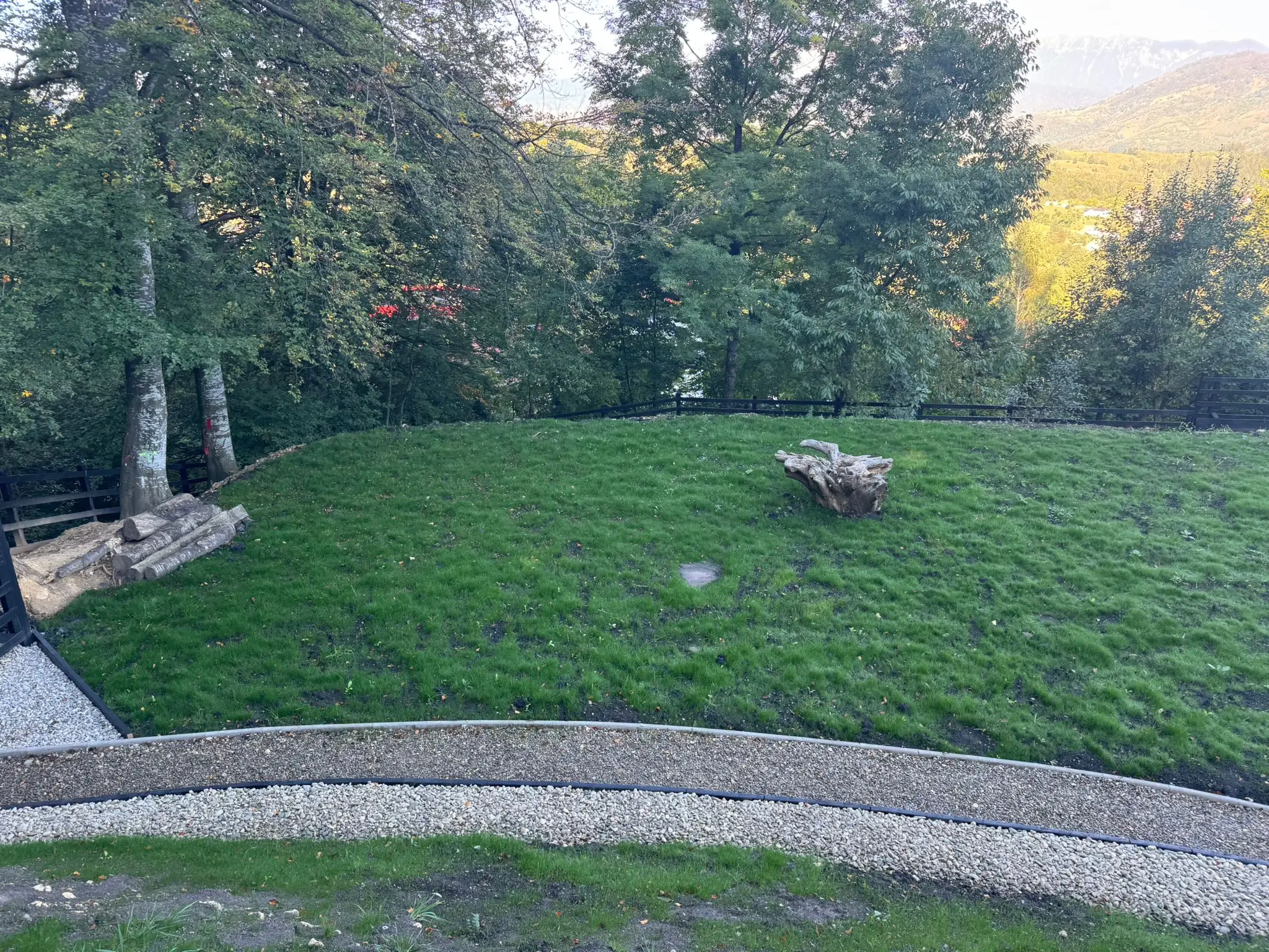 Grădină amenajată cu gazon și borduri de pietriș, cu vedere spre munte